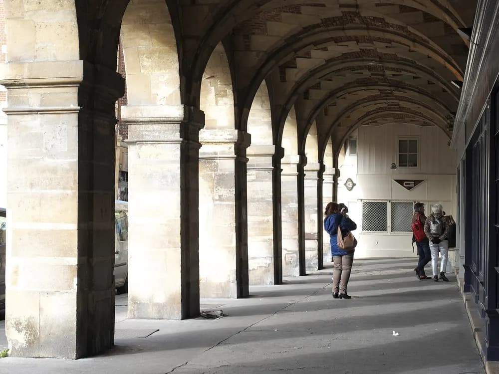 Galerie d’arcades voûtées de la place des Vosges, à Paris.